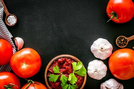 Homemade tomato sause near ingredients - garlic, spices - on black background top-down.の写真素材