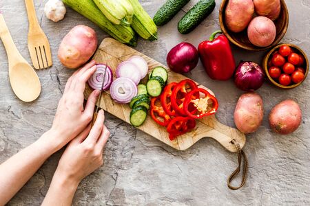 Hands cut pepper on wooden board on greyの写真素材