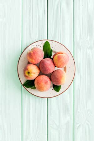 Summer fruits. Ripe red peaches on plate on green wooden table top-down.の写真素材
