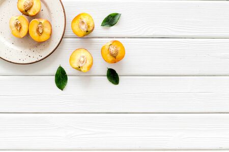 Healthy food. Ripe sliced peaches on plate on white table top-down.