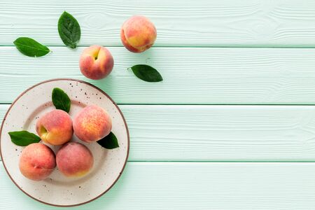 Summer fruits. Ripe red peaches on plate on green wooden table top-down copy spaceの写真素材