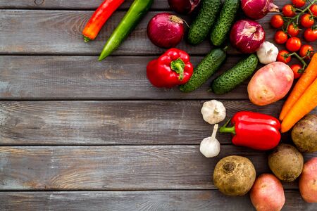 Set of autumn vegetables - potato, cucumber, carrot, greenery - on dark wooden background top-down copy space frameの写真素材