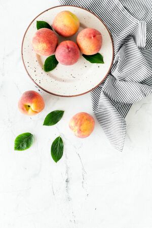 Summer lunch. Red peaches on white background with tablecloth and leaves top-down copy spaceの写真素材