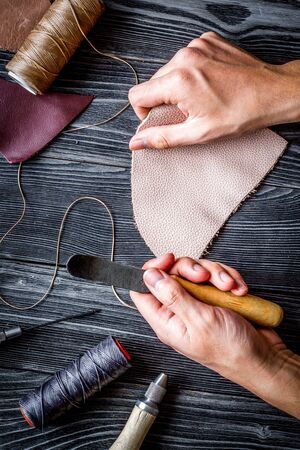 work in leather shop on dark wooden background top view