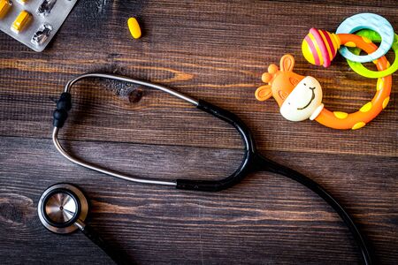 children doctor work with stethoscope and toys top view on wooden backgroundの写真素材