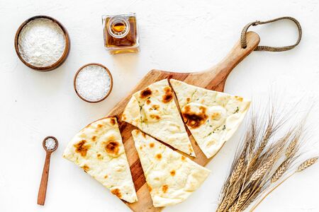 Focaccia ingredients. Wheat ears, flour, oil near bread on white background top-down