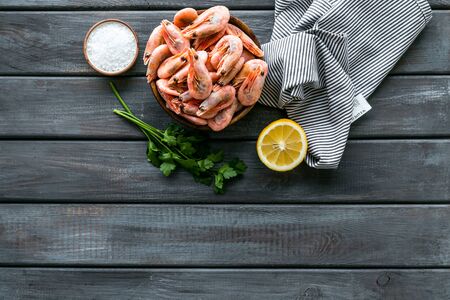 Shrimps for mediterranean salad - with lemon and greeenery - on wooden desk top view copy spaceの写真素材