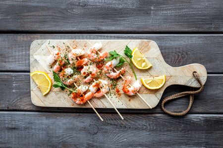 Shrimp skewers on cutting board on wooden tableの写真素材