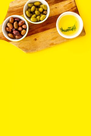 Green and res olives with oil on yellow background. Top viewの写真素材