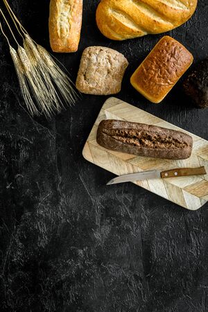 Homemade bread with wheat ear on dark kitchen desk. Top view