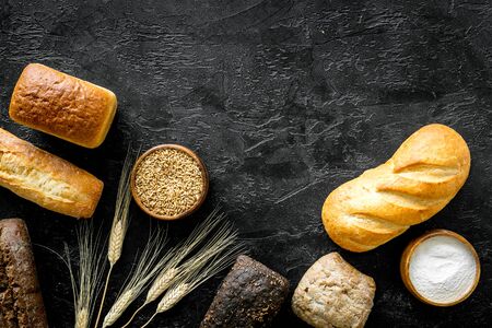Homemade bread with wheat ear on dark kitchen desk. Top view
