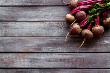 Organic beetroots with green tops and leaves on wooden dark desk. Top viewの写真素材