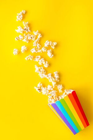 Popcorn in paper cup on yellow desk top viewの写真素材