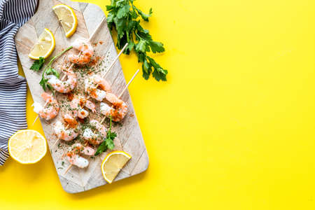 Shrimp skewers - appetizer in mediterranean kitchen - on yellow table top view copy spaceの写真素材