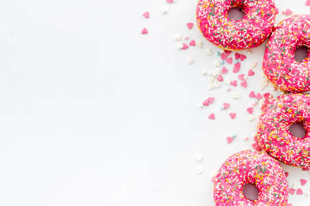 Pink berry donuts flat lay, top view. Glazed and sprinkles doughnuts