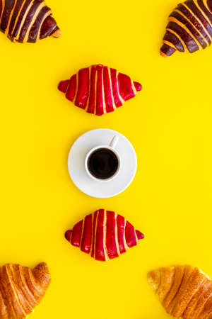 Coffee and croissants on yellow background top view