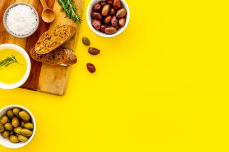 Mediterranean olives near bread on cutting board top view copy space