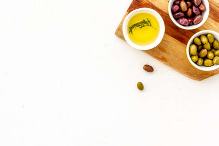 Green and black olives, olive oil in bowls on cutting board top-down copy spaceの写真素材