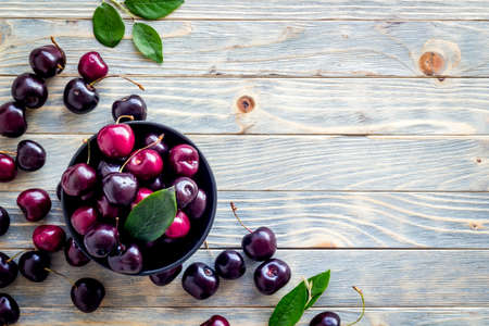 Layout of sweet cherries with leaves, top view, copy space