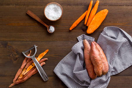 Raw orange sweet potato on cutting board, top viewの写真素材