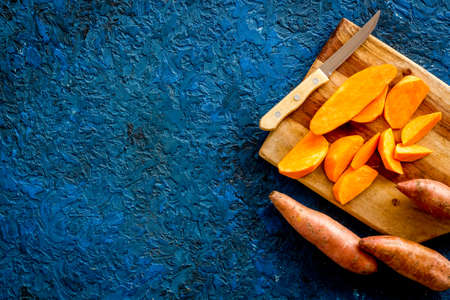 Overhead view of sweet potato sliced on kitchen board. Top view