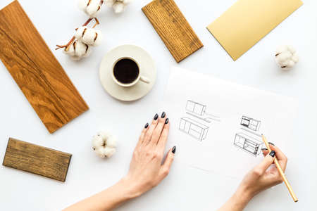 Interior designers hands drawing sketch blueprint with material color samples