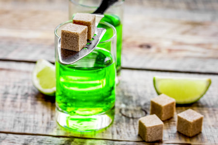 absinthe shots with lime slices and sugar on wooden table background