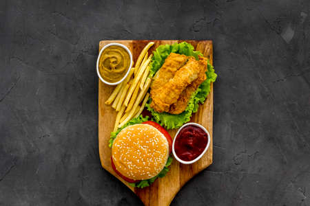 Fast food set. Delicious burger with french fries on wooden cutting board