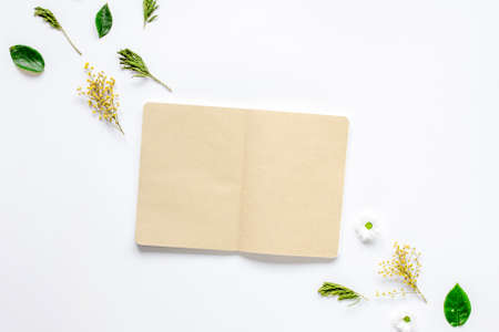 Petals and copybook on white table background top view mock up