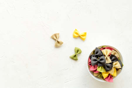 Italian farfalle pasta in bowl. Raw multicolored farfalle pasta, overhead viewの写真素材