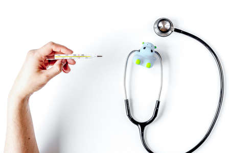stethoscope, thermometer and hands on doctors office desk background top view mock up