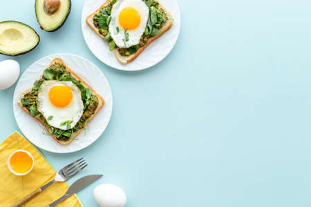 Breakfast with avocado toasts and fried eggs, top view