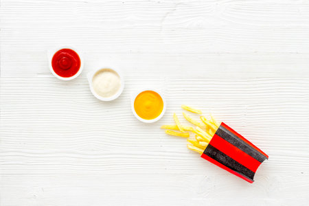 Patatoes french fries in red paper box with different sauces