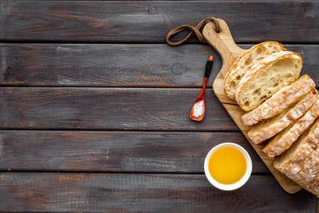 Sliced bread ciabatta with oil on cutting board, top view