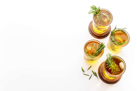 A lot of glasses of lemonade with cold tea and rosemary