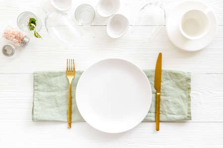 Tableware set with empty plate with dishware and glasses on napkin