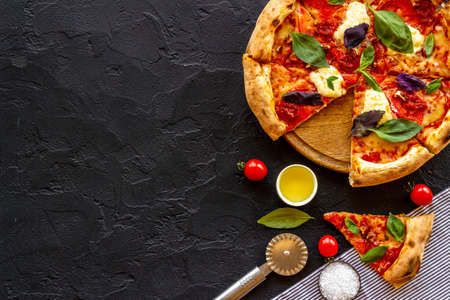 Cut into slices italian pizza with tomatoes cheese and basilの写真素材