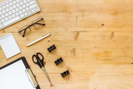 Office desk table with equipment - computer keyboard and notepad, top viewの写真素材