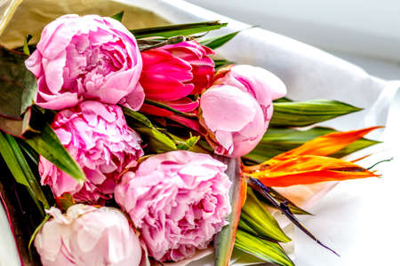 Bouquet of peonies in kraft paper on windowsillの写真素材