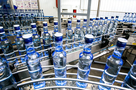 Many bottles on conveyor belt in factory, production of alcohol drink