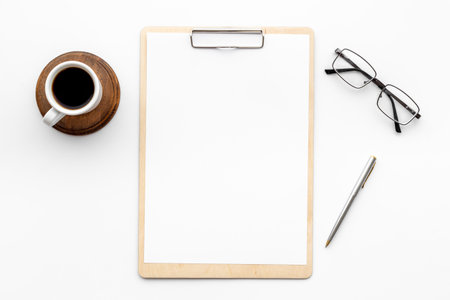 White office desk table with empty paper on clipboardの写真素材