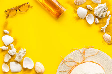 Beach sand and seashells with straw hat and bottles od sunscreenの写真素材
