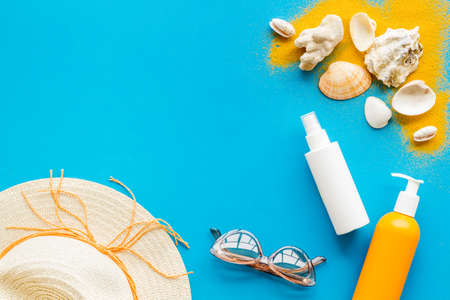 Beach sand and seashells with straw hat and bottles od sunscreenの写真素材
