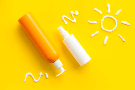 Sunscreen in bottles flatlay with sun made of white cream