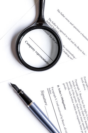 Signing the contract with pen and magnifier in business work top view