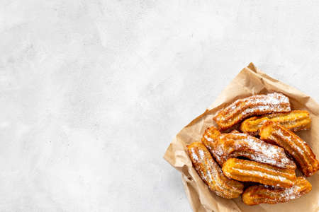 Churros with powdered sugar on baking paper. Fat fast food sweetsの写真素材