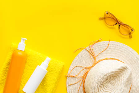 Straw hat and suntanning lotion on towel. Skin care with UV protection cosmetic
