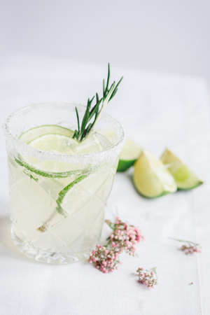 sweet fresh cocktail with flowers and cut lime on stone desk background
