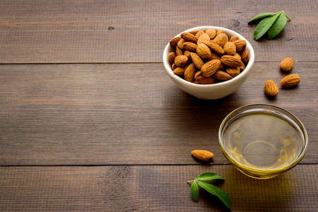 Sweet almond oil in glass jar and almond seeds with green leafの写真素材