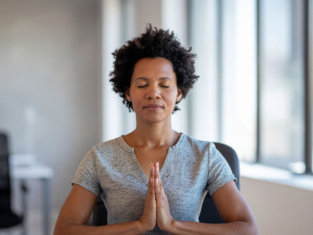 Portrait of businesswoman meditating while sitting at desk in officeの素材